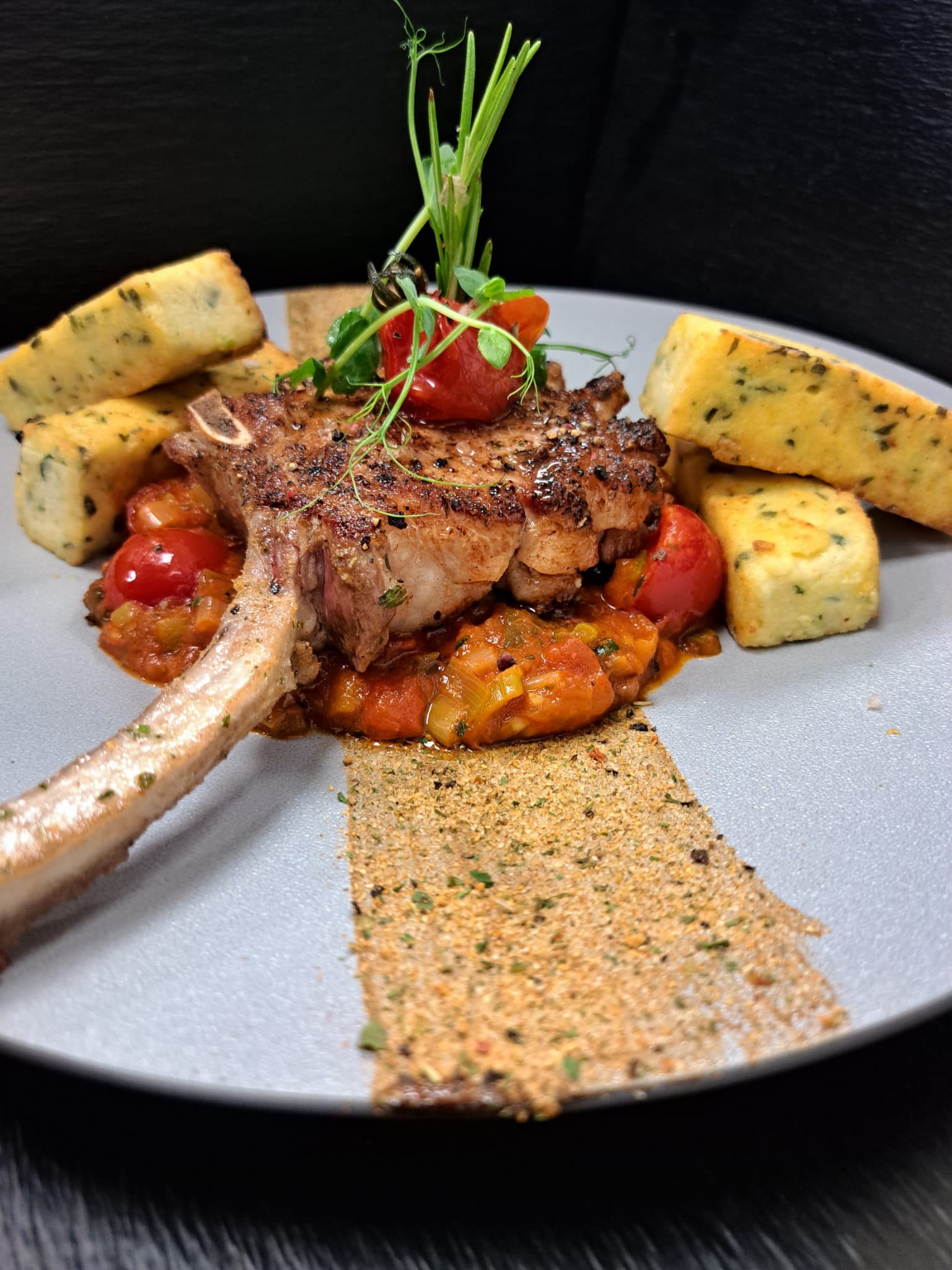 Dry Aged Tomahawk vom Ibericoschwein auf Tomatengemüse mit Kräuter-Polenta bei Salzburg schmeckt