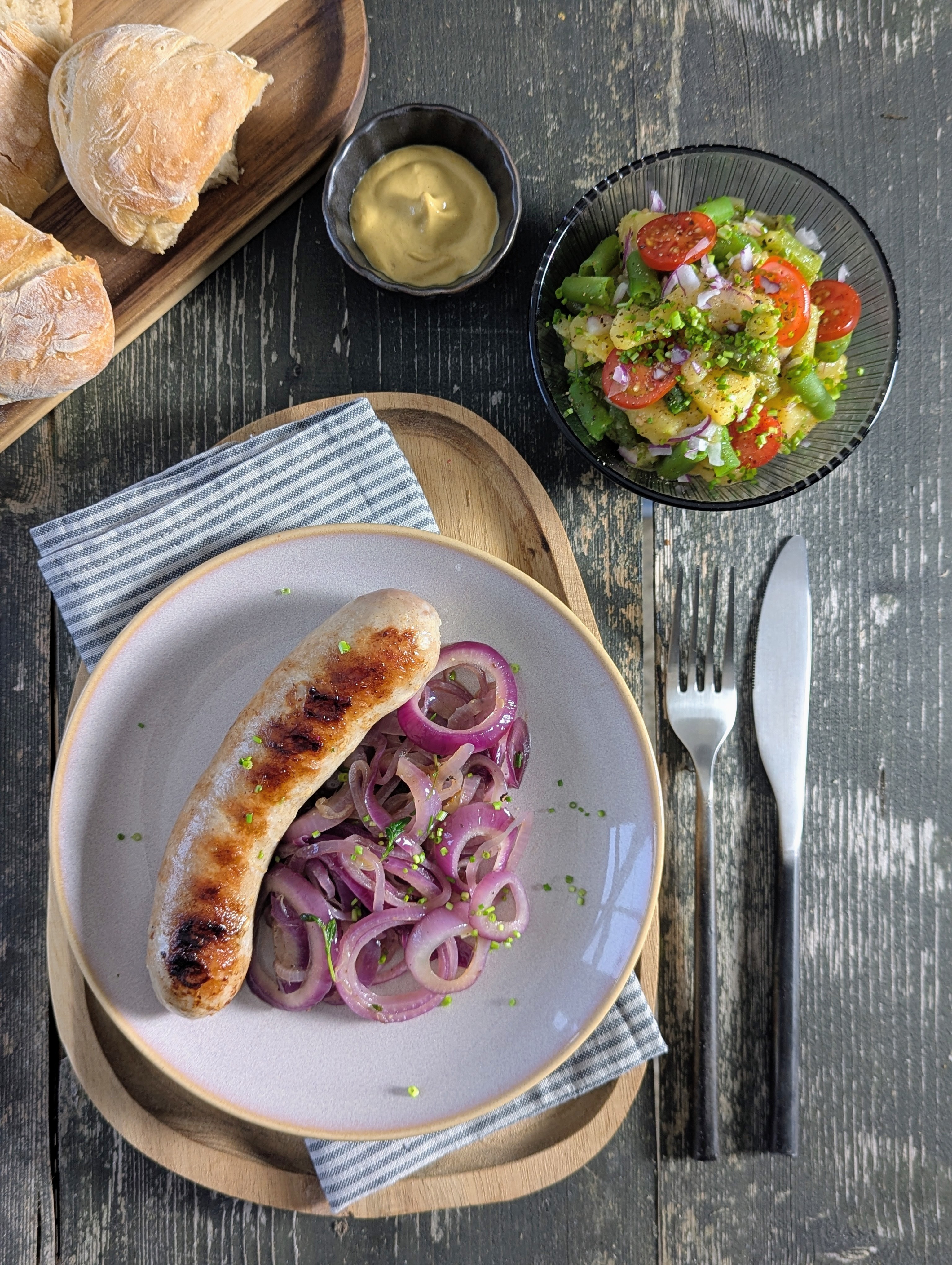 Gebratene Grillwurst mit karamellisierten Zwiebeln und Kartoffelsalat bei Salzburg schmeckt