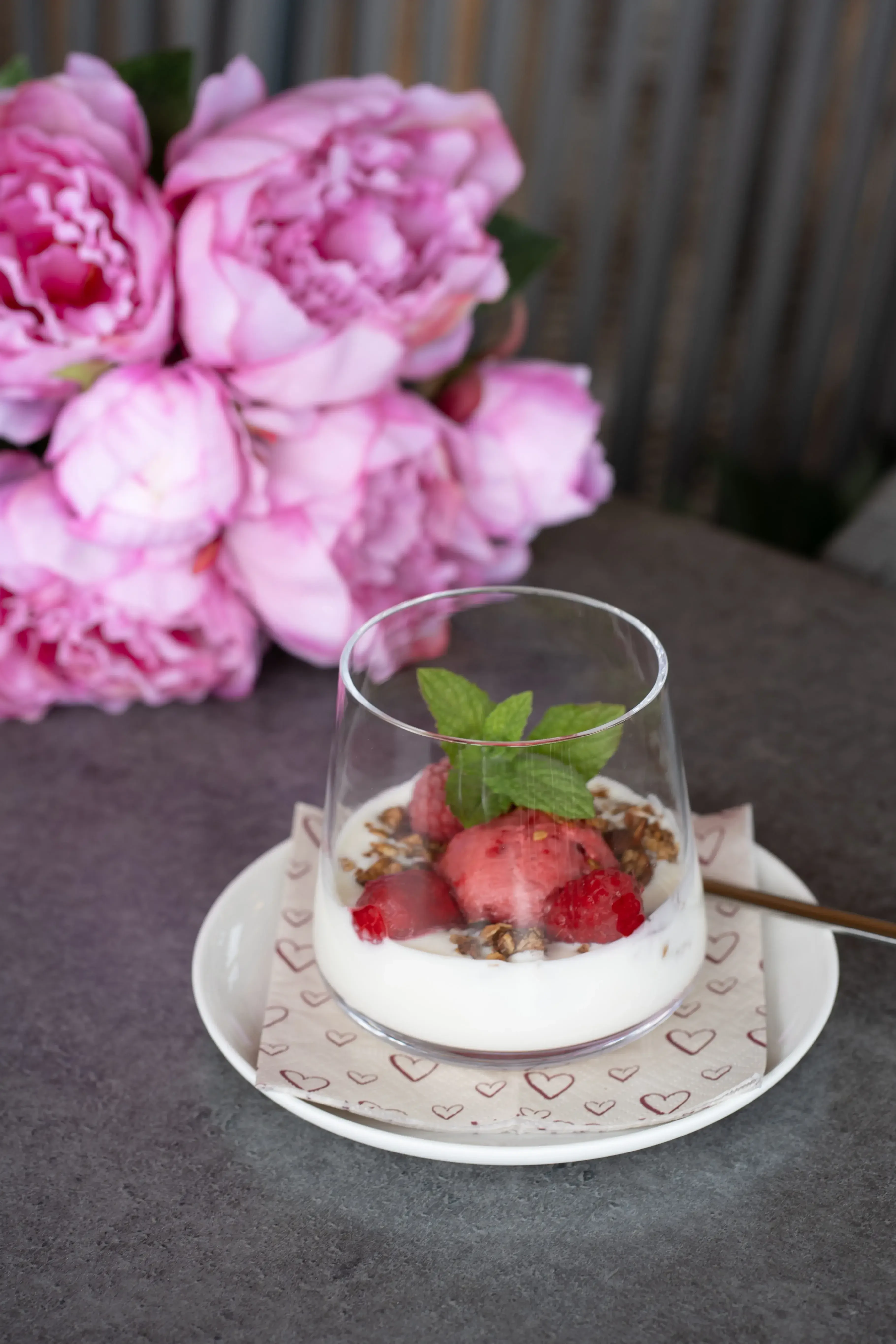 Joghurt mit Erdbeere im Glas im Hintergrund Pfingsrosenstrauß